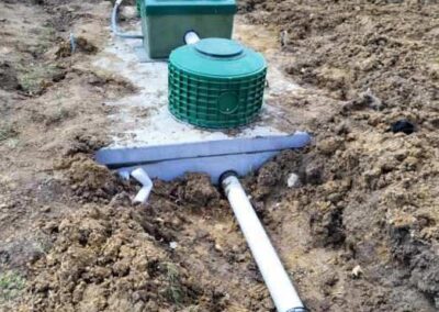 Septic tank riser lids and PVC aeration pipes in a dirt lot.